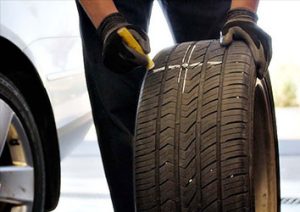 A person is holding the tire of a car.