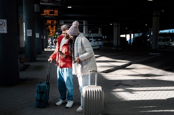 Two people standing next to a luggage bag.